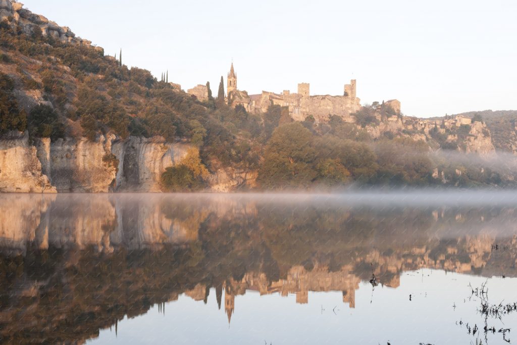 Vue panoramique du village d’Aiguèze en automne qui se reflette dans l’eau de l’Ardèche