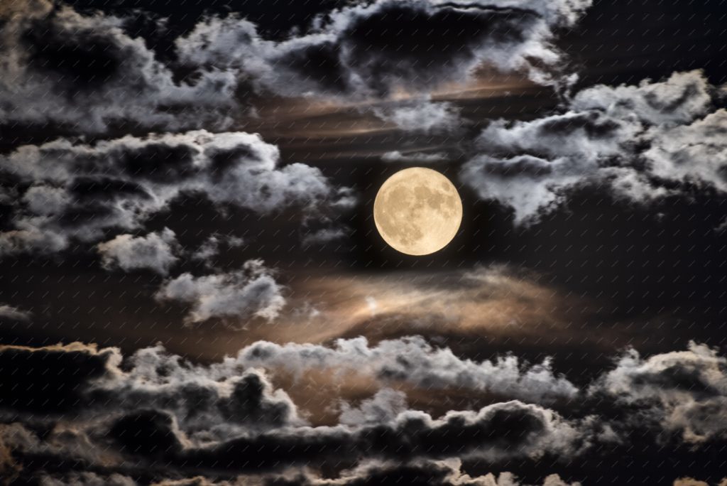 Pleine lune brille sur un ciel nuageux une nuit d'été